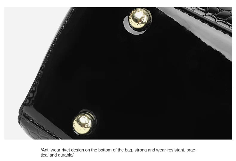 Schwarze Handtasche mit goldenen Nieten, glänzend, krokodillederähnliche Textur, elegant.