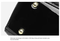 Schwarze Handtasche mit goldenen Nieten, glänzend, krokodillederähnliche Textur, elegant.