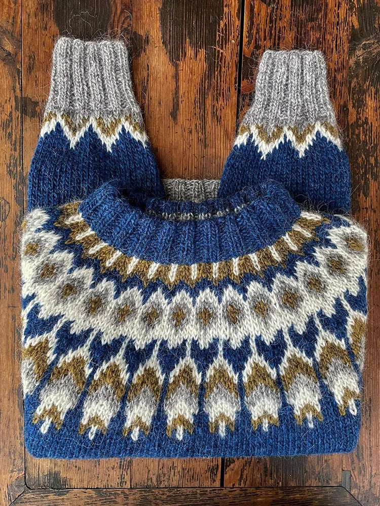 Blauer Norwegerpullover aus Wolle mit traditionellem Muster auf rustikalem Holztisch.