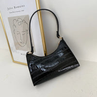 Schwarze Krokodilleder-Handtasche, elegant, modern, mit goldenen Details, vor Kunstwerk.