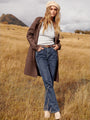 Frau in braunem Mantel und blauer Jeans in Herbstlandschaft, Mode, Outdoor, stilvoll, elegant.