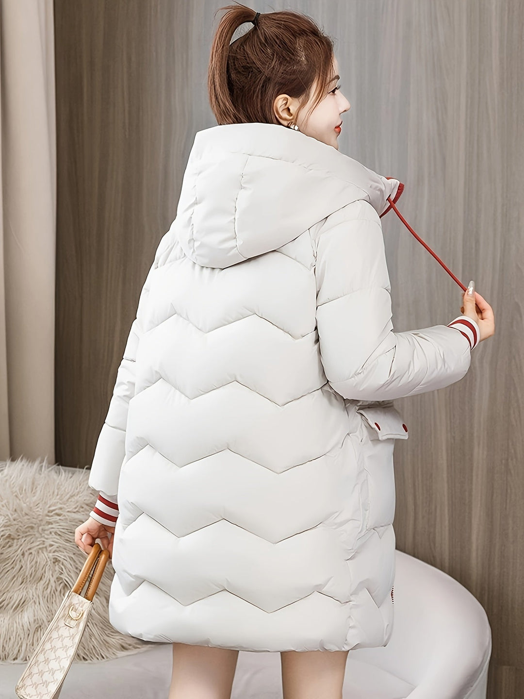 Frau in weißem Daunenmantel mit Kapuze, Wintermode, warm, stilvoll, Rückansicht.