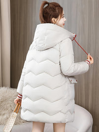 Frau in weißem Daunenmantel mit Kapuze, Wintermode, warm, stilvoll, Rückansicht.