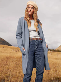 Frau in blauem Mantel und Jeans, beige Mütze, Herbstlandschaft, Mode, Outdoor-Bekleidung.