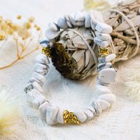 Weiße Howlith-Armband mit goldenen Akzenten auf beigem Stoff, Schmuck, Natursteine, Boho-Stil.