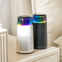 Zwei tragbare Luftreiniger, weiß und schwarz, mit LED-Licht auf einem Tisch.