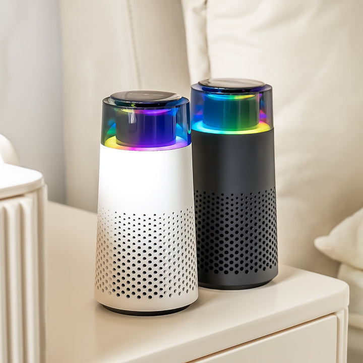 Zwei tragbare Luftreiniger, weiß und schwarz, mit LED-Licht auf einem Tisch.