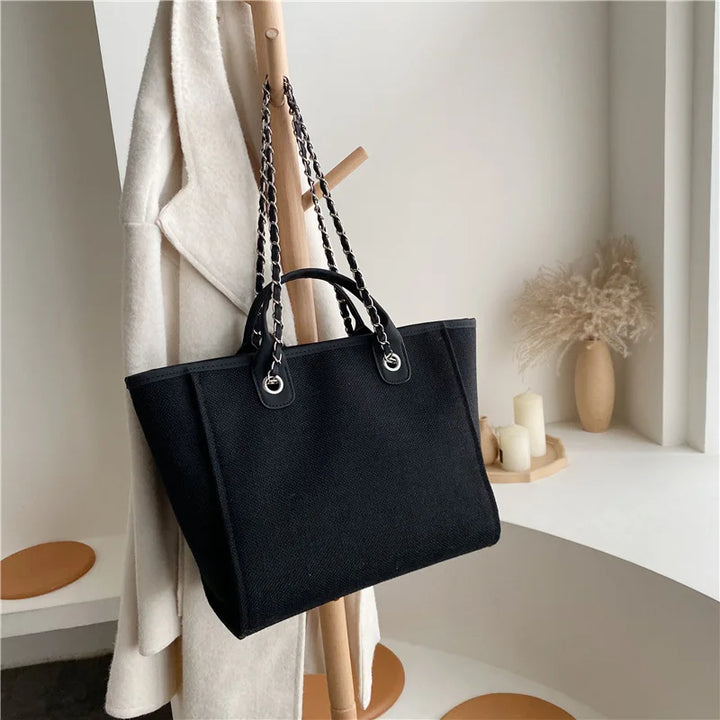 Schwarze Damenhandtasche aus Leder mit Kettenriemen, elegant, modern, stilvoll, Accessoire.