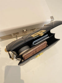 Schwarze Lederhandtasche mit goldener Kette, geöffnet, zeigt Innenfächer und Accessoires.