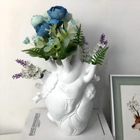 Weiße Herzvase mit blauen und lila Kunstblumen, dekorative Wohnaccessoires.