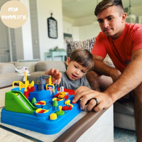 Vater und Kind spielen mit buntem Spielzeugset auf Tisch im Wohnzimmer.