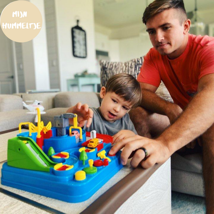 Vater und Kind spielen mit buntem Spielzeugset auf Tisch im Wohnzimmer.