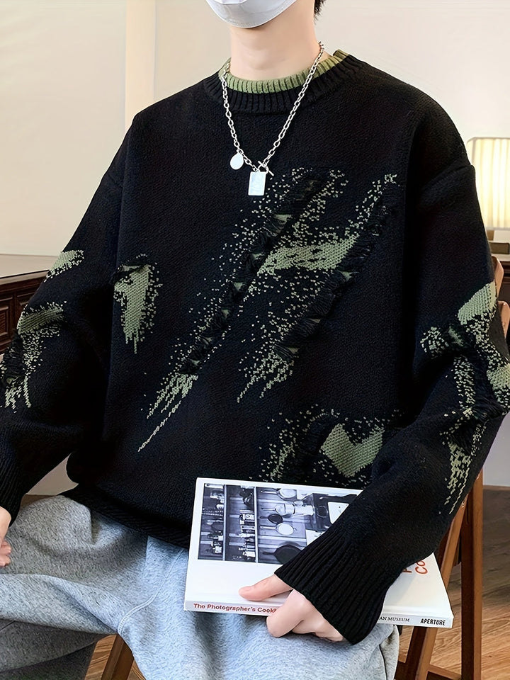 Mann in schwarzem Strickpullover mit grünem Muster, silberner Kette, hält ein Buch.