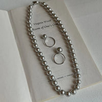 Perlenkette und Ohrringe auf Buchseite, silber, eleganter Schmuck, Accessoires, Geschenkidee.