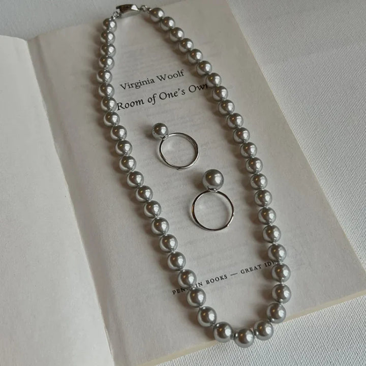 Perlenkette und Ohrringe auf Buchseite, silber, eleganter Schmuck, Accessoires, Geschenkidee.