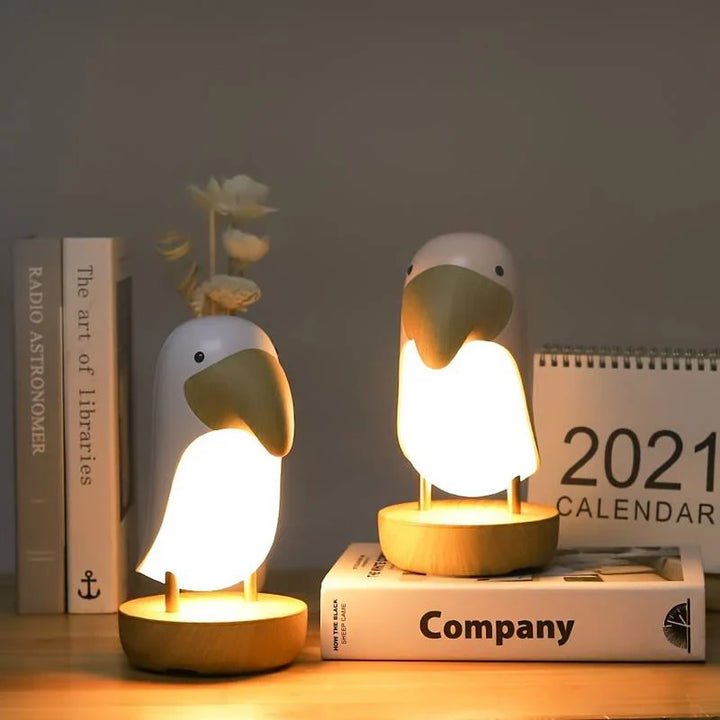 Zwei Pinguin-Nachttischlampen aus Holz auf Bücherregal, warmes Licht, modernes Design.