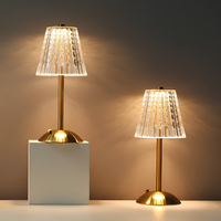 Zwei goldene Tischlampen mit transparentem Lampenschirm, modernes Design, warmes Licht.