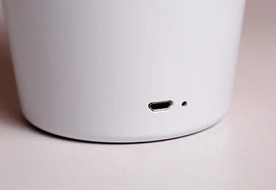 Weiße Bluetooth-Lautsprecherbasis mit Micro-USB-Anschluss, modernes Design.