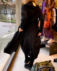 Person in schwarzem Mantel im Schaufenster, Modegeschäft, moderne Kleidung, Herbstmode.