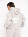 Frau in grauem Hoodie mit "White Fox" Aufdruck, Kapuze, lässiger Stil, Rückansicht.