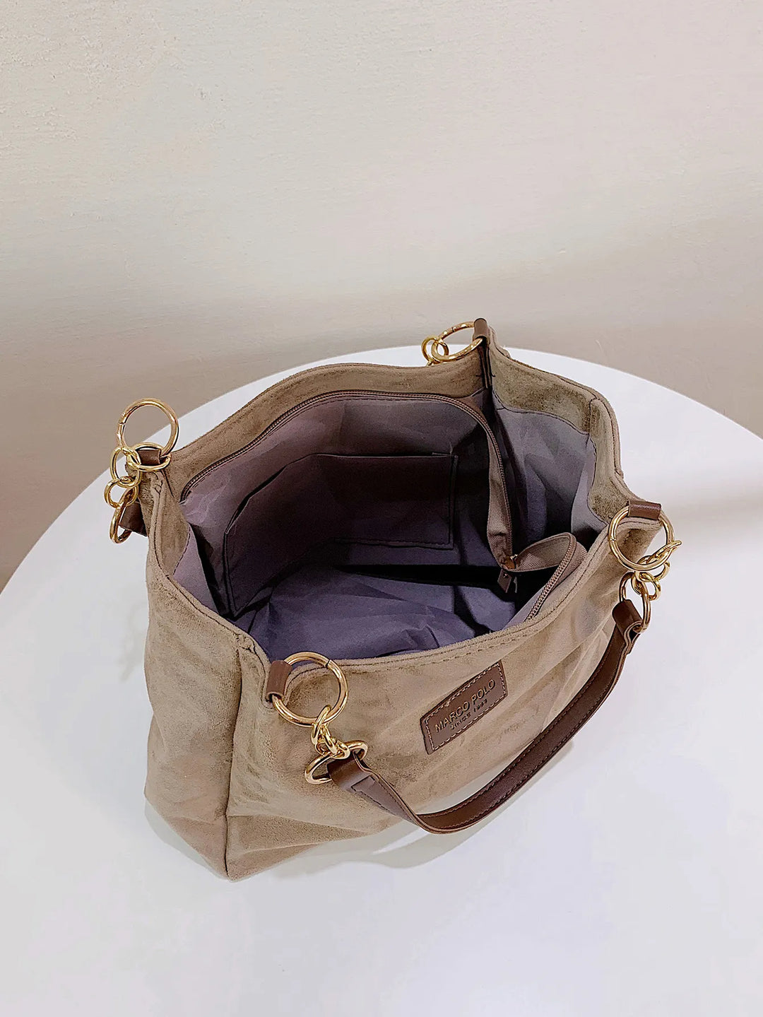 Beige Canvas-Handtasche mit braunen Ledergriffen und goldenen Ringen, offene Innenansicht.