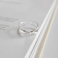 Silberner, verstellbarer Ring mit elegantem, gedrehtem Design auf weißem Hintergrund.