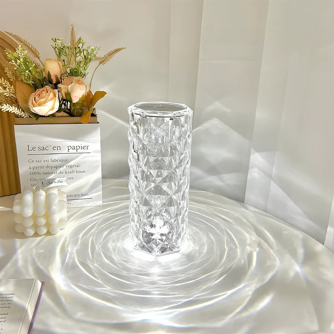 Kristallvase mit geometrischem Muster, transparent, auf weißem Tisch, dekoriert mit Blumen.