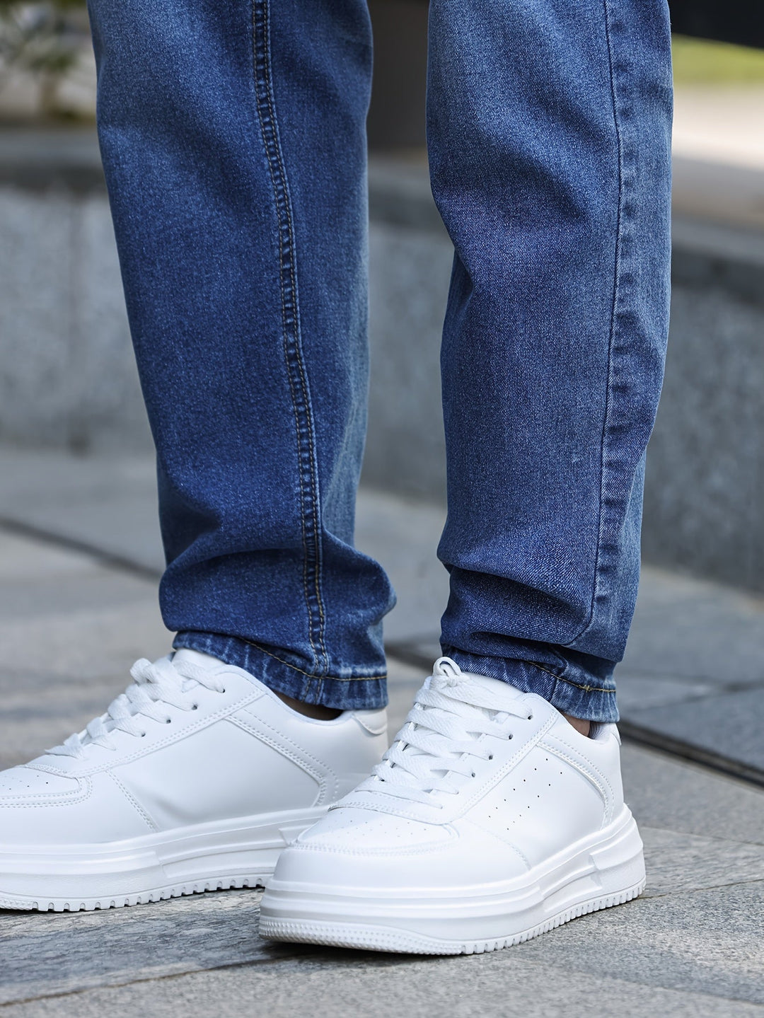 Weiße Sneaker aus Leder, getragen mit blauen Jeans, Straßenszene, modisch, bequem.