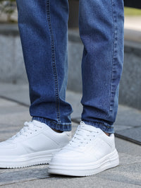 Weiße Sneaker aus Leder, getragen mit blauen Jeans, Straßenszene, modisch, bequem.