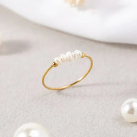 Goldener Ring mit kleinen weißen Perlen, minimalistisches Schmuckdesign, eleganter Damenring.
