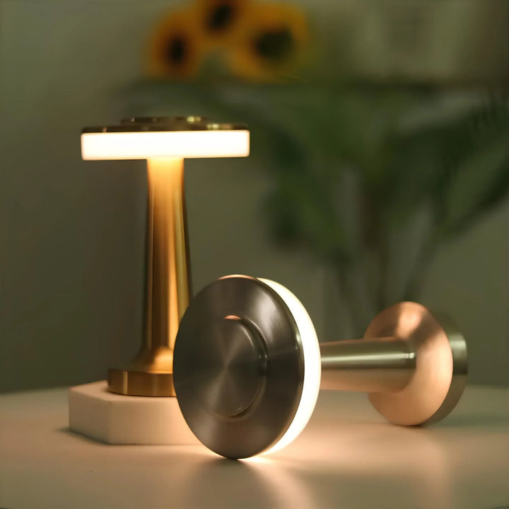 Zwei moderne LED-Tischlampen aus Metall, gold und silber, auf weißem Tisch, Hintergrund unscharf.