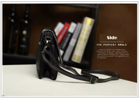 Schwarze Ledertasche mit verstellbarem Riemen, seitliche Ansicht, auf Tisch vor Bücherregal.