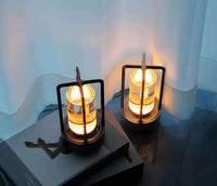 Zwei moderne LED-Tischlampen mit schwarzem Metallrahmen und warmem Licht auf dunklem Tisch.