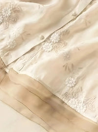 Beige Seidenstoff mit floraler Stickerei, luxuriöses Material für elegante Mode und Dekoration.