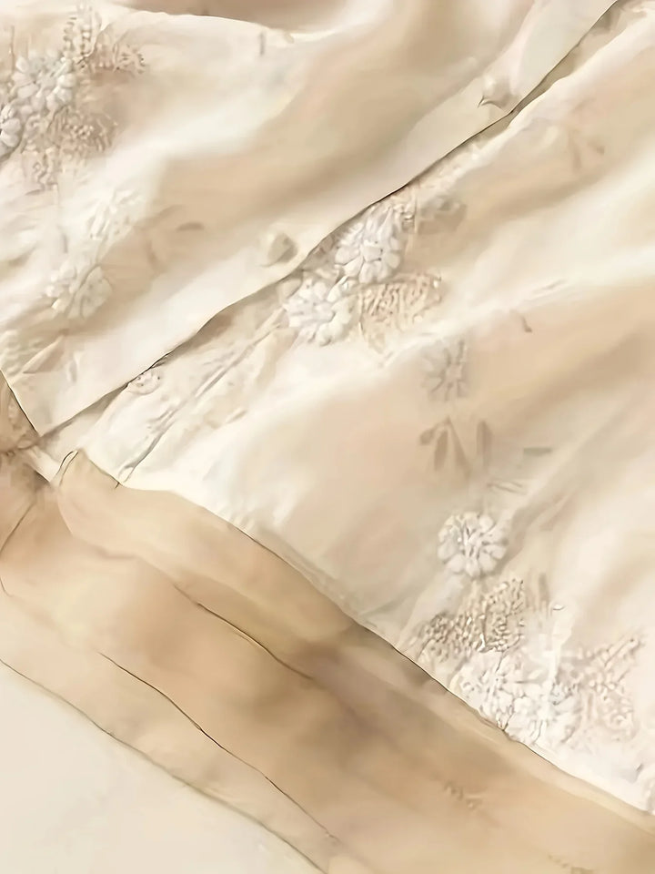 Beige Seidenstoff mit floraler Stickerei, luxuriöses Material für elegante Mode und Dekoration.