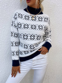 Frau in weißem Strickpullover mit Schneeflockenmuster, blauer Rollkragen, weiße Hose.