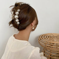 Frau mit Perlen-Haarklammer, eleganter Haarschmuck, Hochsteckfrisur, weißes Oberteil.