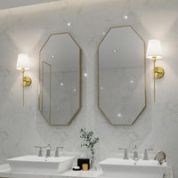 Zwei achteckige Spiegel mit goldenen Rahmen, Wandlampen, Doppelwaschbecken, modernes Badezimmerdesign.