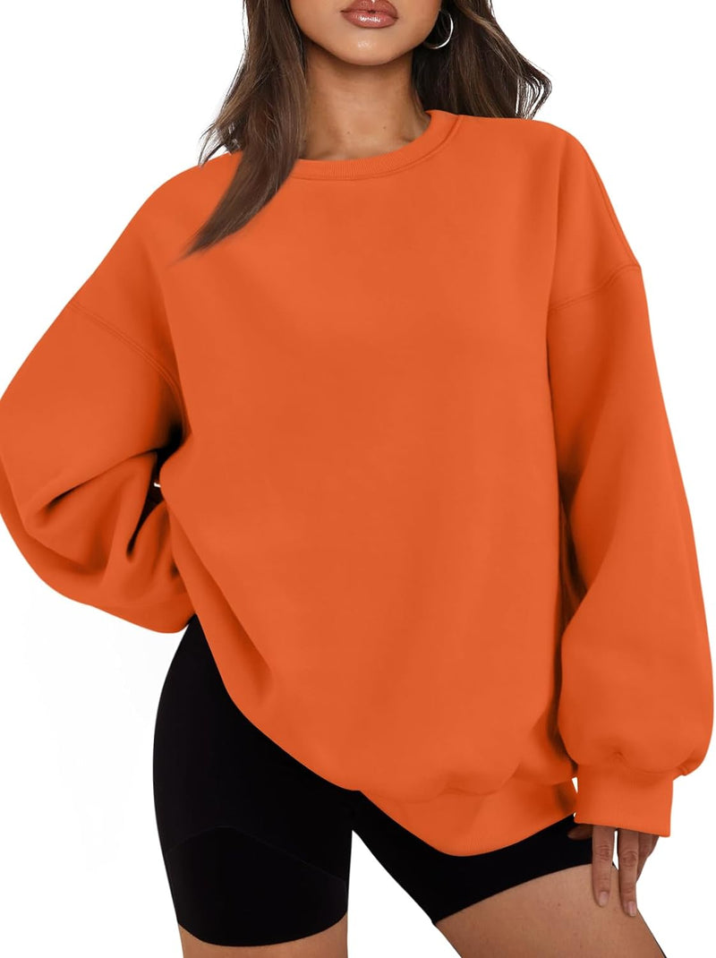 Frau in orangefarbenem Oversize-Pullover und schwarzen Shorts, modisch, lässig, bequem.