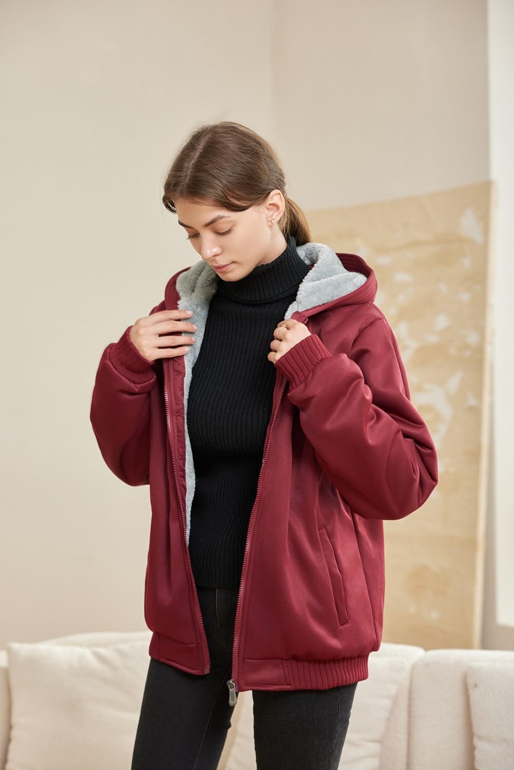 Frau in roter Kapuzenjacke, schwarzem Rollkragenpullover, gemütliche Wintermode.