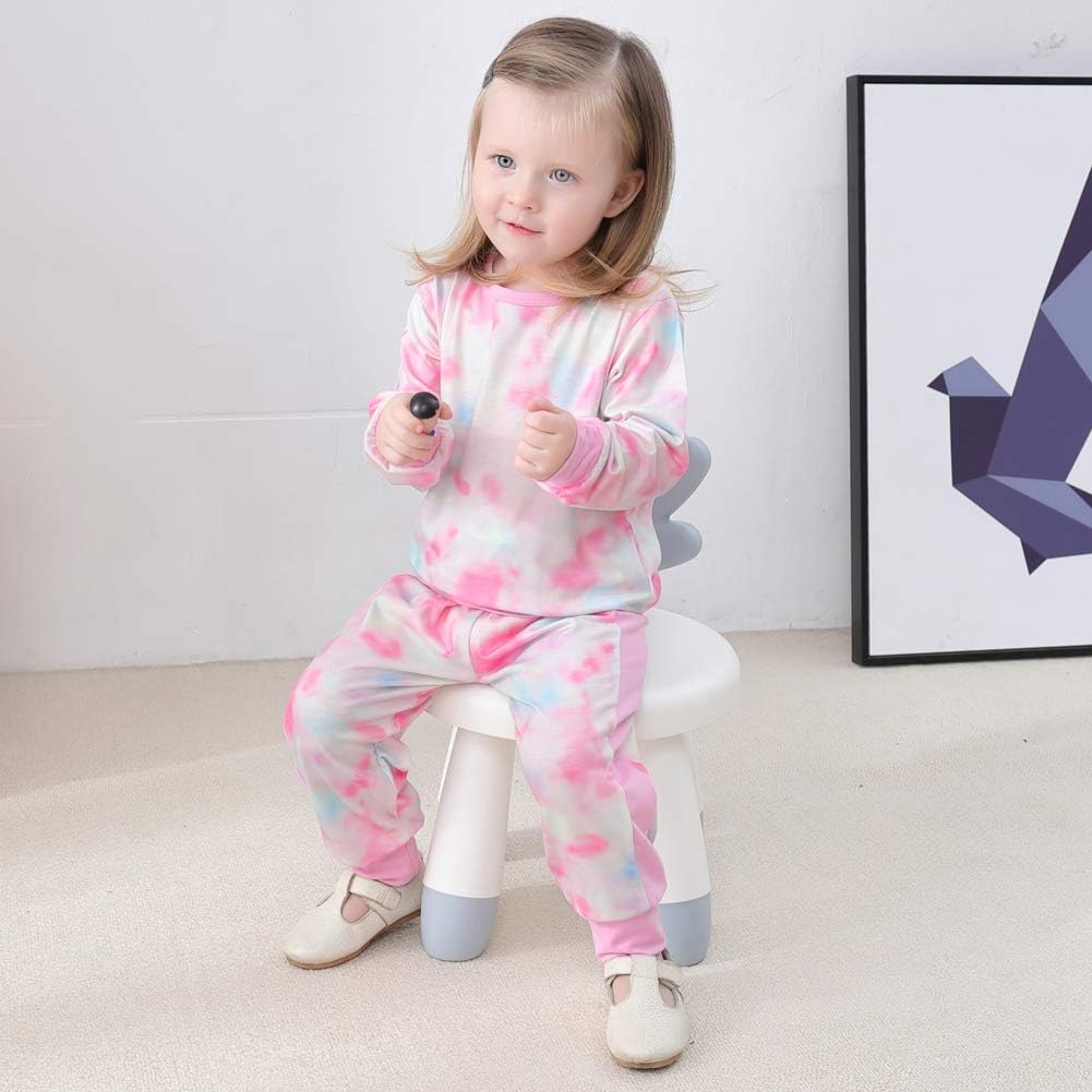 Kleinkind in rosa-weißem Batik-Pyjama auf Stuhl, Kinderzimmer, gemütliche Kleidung.