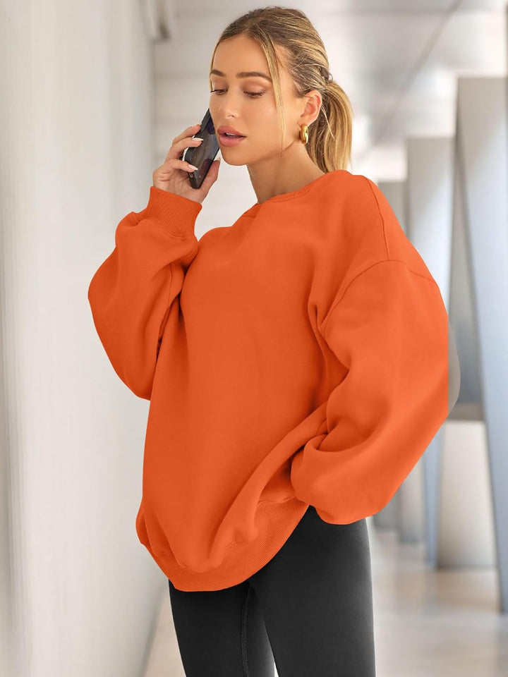Frau in orangefarbenem Oversize-Pullover, telefonierend, moderne Mode, Freizeitkleidung.