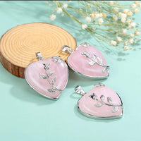 Herzförmiger Rosenquarz-Anhänger mit Silberblatt-Design auf Holzscheibe, Schmuckfotografie.