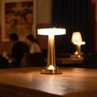 Goldene LED-Tischlampe auf Holztisch, modernes Design, warmes Licht, ideal für Wohnzimmer.