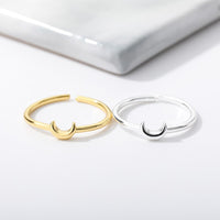 Zwei offene Ringe, gold und silber, mit Halbmond-Design auf weißem Hintergrund.