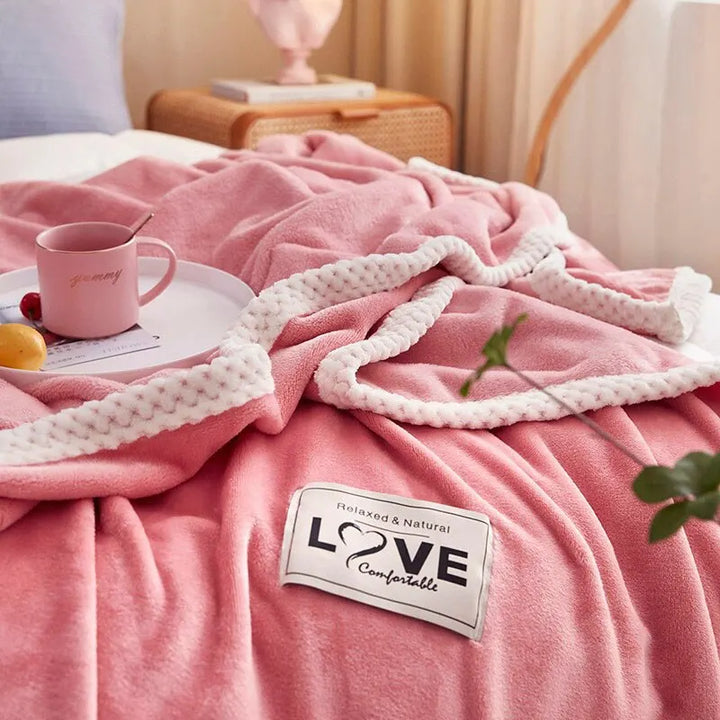 Rosa Kuscheldecke mit weißem Rand auf Bett, Tasse und Tablett, gemütliches Schlafzimmer.