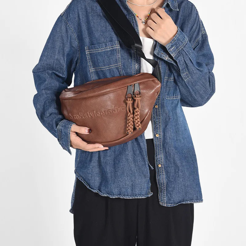 Frau mit brauner Leder-Gürteltasche, Jeanshemd, schwarze Hose, modisch, lässig.