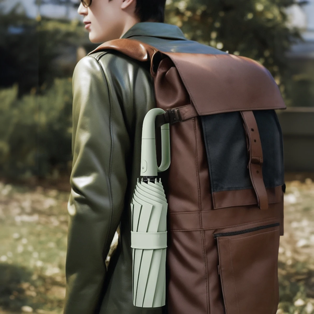 Mann mit brauner Ledertasche und grünem Regenschirm im Freien.