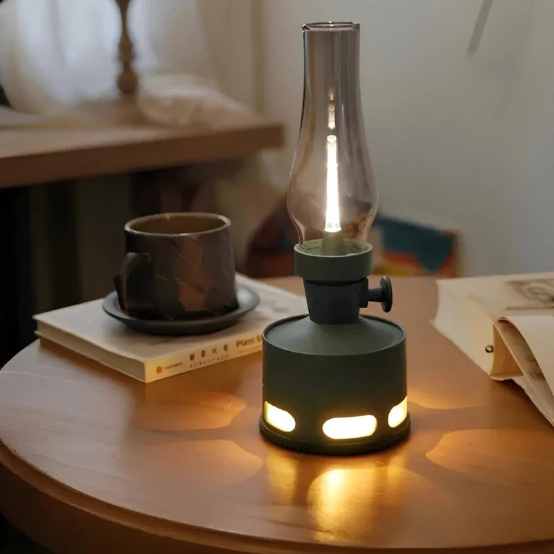 Grüne LED-Laterne auf Holztisch neben Tasse und Buch, gemütliche Beleuchtung.