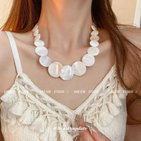 Weiße Perlenkette auf cremefarbenem Spitzenkleid, eleganter Schmuck für Damen.